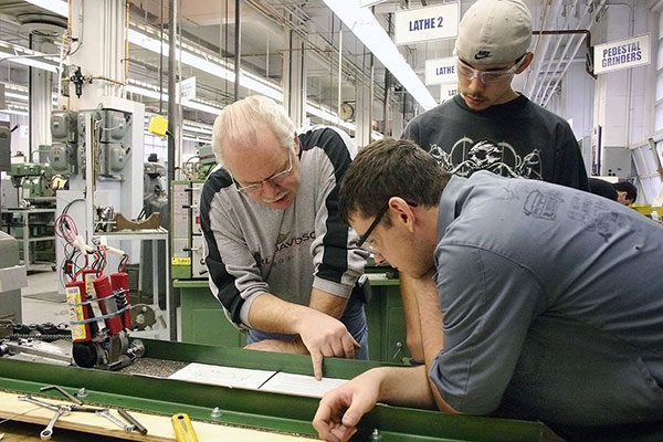 A photo of two interns listening to their instructor